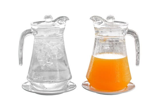 orange juice and water in pitcher on plate