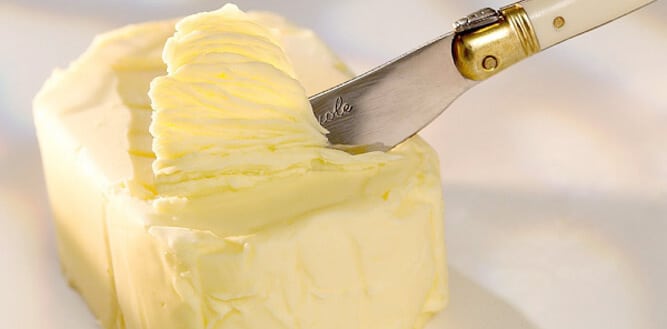 manteiga deliciosa sendo retirada com uma faca